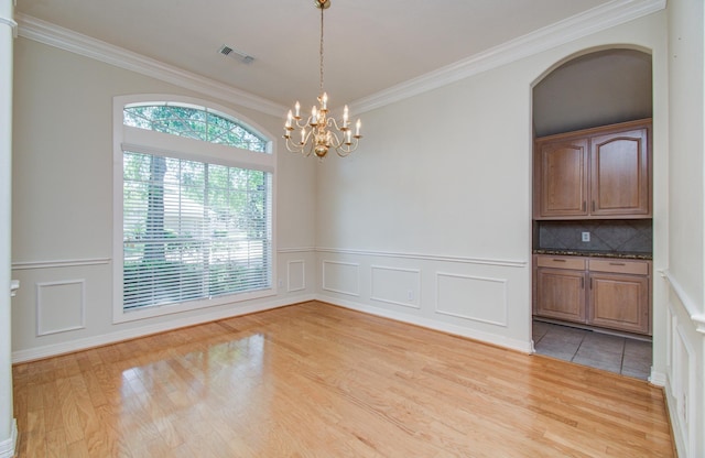 16214 Lobo Ln, Spring, TX 77379 - unfurnished dining area with light wood-style flooring, ornamental molding, a chandelier, wainscoting, and a decorative wall