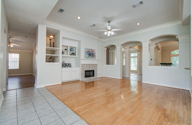 16214 Lobo Ln, Spring, TX 77379 - unfurnished living room with a ceiling fan, plenty of natural light, ornate columns, a fireplace, and ornamental molding