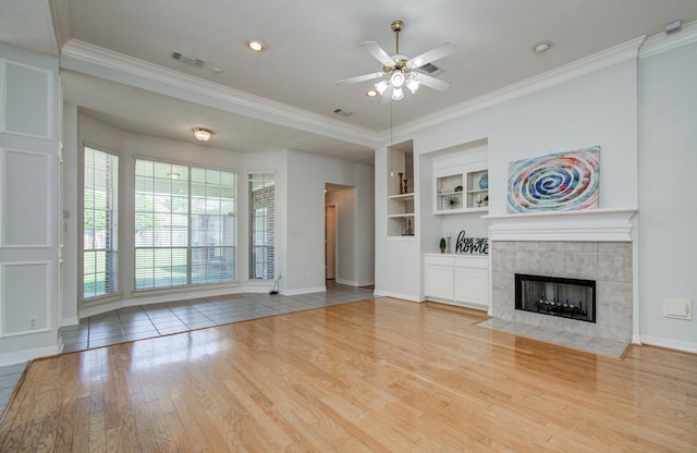 16214 Lobo Ln, Spring, TX 77379 - unfurnished living room featuring a ceiling fan, wood finished floors, built in shelves, a fireplace, and crown molding