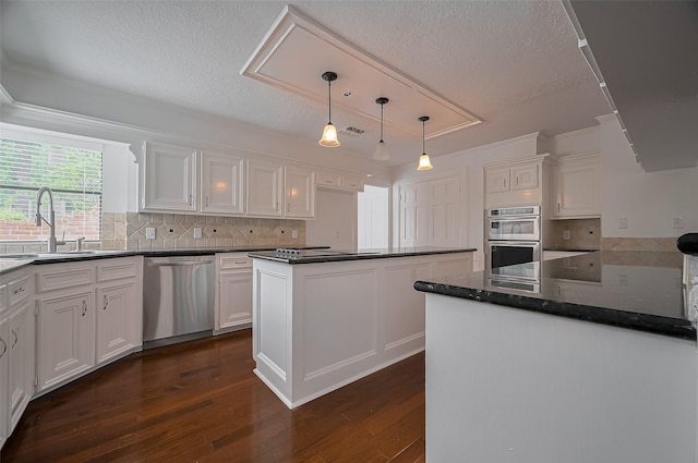 9411 Fenchurch Dr, Spring, TX 77379 - kitchen with stainless steel appliances, white cabinets, dark wood-type flooring, a textured ceiling, and tasteful backsplash