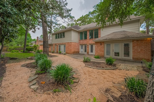9411 Fenchurch Dr, Spring, TX 77379 - back of property featuring french doors, brick siding, a patio area, and a shingled roof