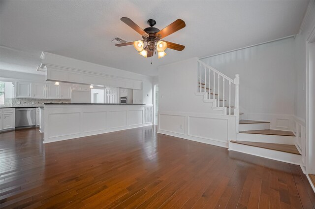 9411 Fenchurch Dr, Spring, TX 77379 - unfurnished living room featuring dark wood-type flooring, stairs, ceiling fan, a decorative wall, and a wainscoted wall