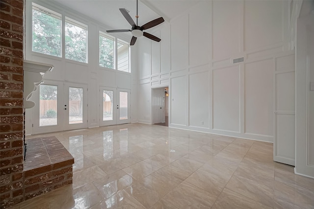 9411 Fenchurch Dr, Spring, TX 77379 - unfurnished living room featuring a decorative wall, a high ceiling, healthy amount of natural light, ceiling fan, and light marble finish flooring