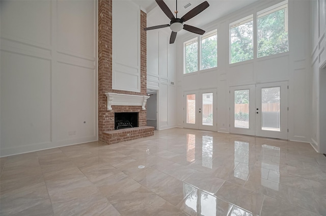 9411 Fenchurch Dr, Spring, TX 77379 - unfurnished living room with a high ceiling, a decorative wall, a ceiling fan, a fireplace, and french doors