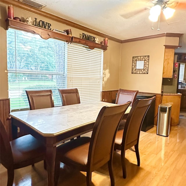 12006 Mill Trail Ln, Houston, TX 77070 - dining room featuring crown molding, light wood-style floors, a wainscoted wall, a ceiling fan, and wooden walls