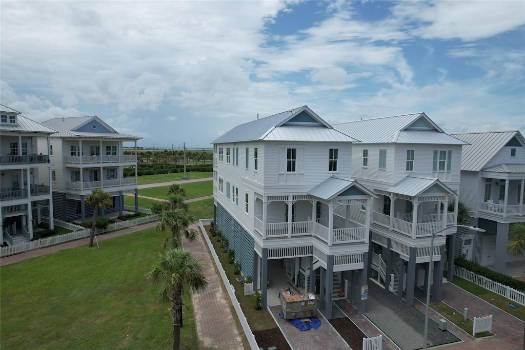 2602 E Seaside Dr, Galveston, TX 77550 - back of house with a metal roof, decorative driveway, a carport, and a yard