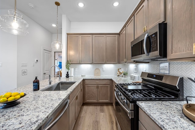 1546 W Tidwell Rd, Houston, TX 77091 - kitchen with stainless steel appliances, light wood finished floors, decorative backsplash, light stone countertops, and hanging light fixtures