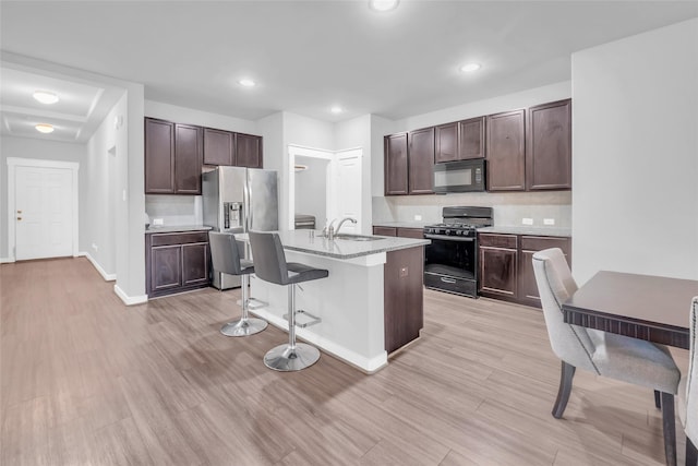12326 Sabine Point Dr, Humble, TX 77346 - kitchen featuring gas range, black microwave, a kitchen breakfast bar, dark brown cabinets, and stainless steel fridge with ice dispenser