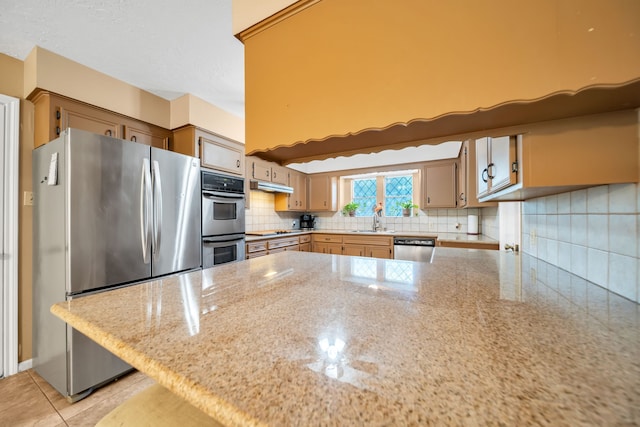 13202 N Decker Dr, Magnolia, TX 77355 - kitchen featuring stainless steel appliances, a peninsula, under cabinet range hood, decorative backsplash, and light stone countertops