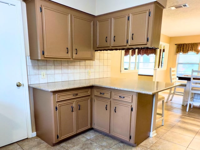 13202 N Decker Dr, Magnolia, TX 77355 - kitchen featuring light countertops, backsplash, light tile patterned flooring, and a kitchen breakfast bar