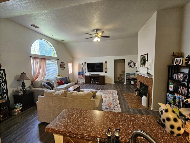 15506 Fir Woods Ln, Cypress, TX 77429 - living area with vaulted ceiling, ceiling fan, dark wood-type flooring, a tile fireplace, and a textured ceiling