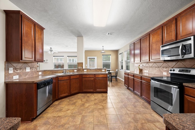 16606 River Wood Ct, Crosby, TX 77532 - kitchen with appliances with stainless steel finishes, tasteful backsplash, healthy amount of natural light, a peninsula, and a textured ceiling