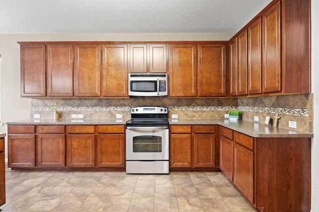 16606 River Wood Ct, Crosby, TX 77532 - kitchen with stainless steel appliances, brown cabinetry, tasteful backsplash, and light stone countertops