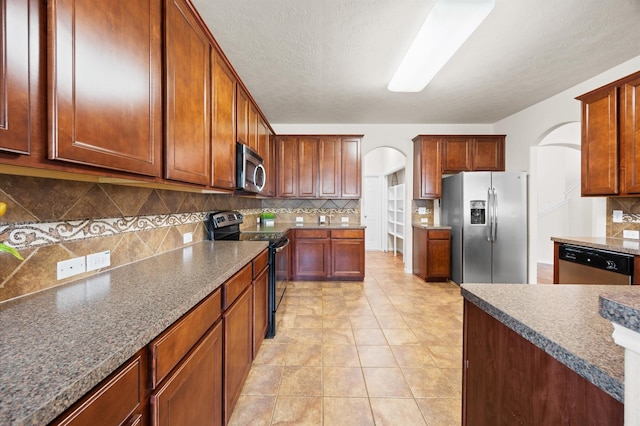 16606 River Wood Ct, Crosby, TX 77532 - kitchen with appliances with stainless steel finishes, arched walkways, backsplash, and light tile patterned floors