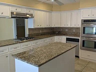 7822 Albin Ln, Houston, TX 77071 - kitchen featuring stainless steel appliances, under cabinet range hood, white cabinets, and dark stone countertops