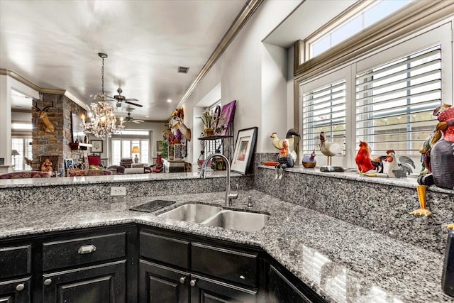 3039 Bayshore Dr, Bacliff, TX 77518 - kitchen featuring dark cabinets, a chandelier, open floor plan, crown molding, and light stone countertops