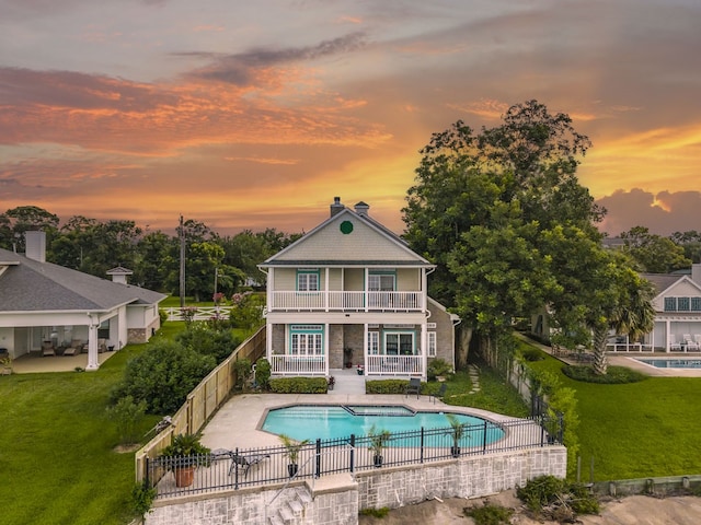 3039 Bayshore Dr, Bacliff, TX 77518 - back of house at dusk featuring a fenced backyard, a balcony, a patio, and a chimney
