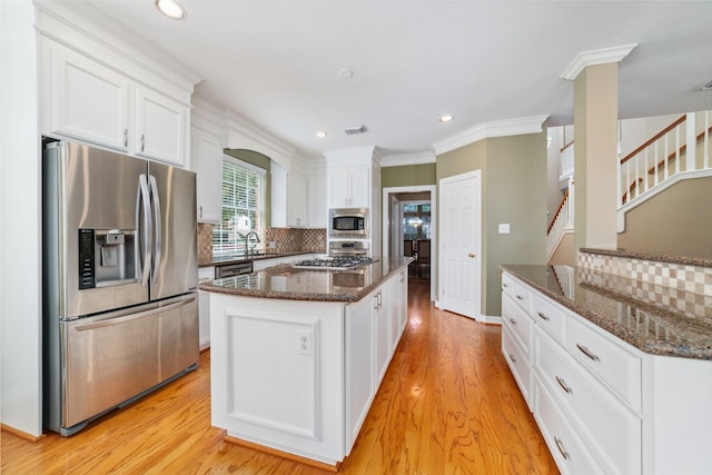 1915 Stormcroft Cir, Katy, TX 77450 - kitchen featuring appliances with stainless steel finishes, white cabinets, tasteful backsplash, light wood-style flooring, and dark stone countertops