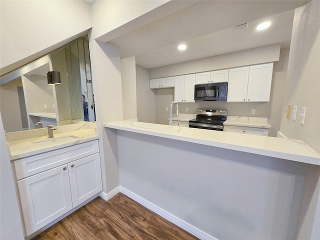 8100 Cambridge St Unit 99, Houston, TX 77054 - kitchen with stainless steel electric range, black microwave, dark wood-type flooring, white cabinetry, and recessed lighting