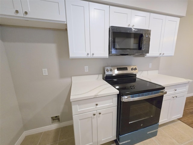 8100 Cambridge St Unit 99, Houston, TX 77054 - kitchen featuring stainless steel electric range, white cabinets, light tile patterned floors, and light stone countertops