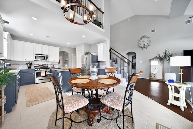 26626 Grey Sparrow Dr, Katy, TX 77494 - dining area with arched walkways, light tile patterned flooring, stairway, a chandelier, and a high ceiling