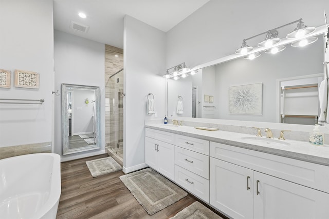 19623 Shores Dr, Galveston, TX 77554 - full bath featuring double vanity, a stall shower, a freestanding bath, and wood finished floors