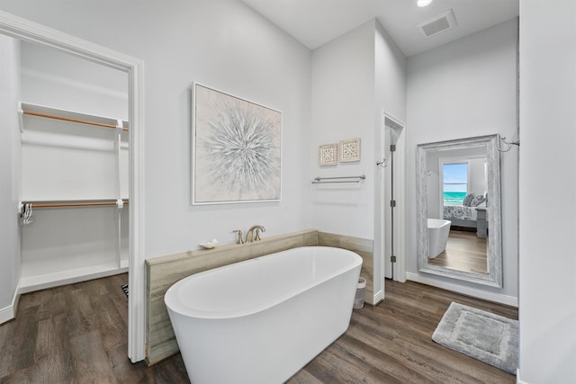 19623 Shores Dr, Galveston, TX 77554 - bathroom featuring a spacious closet, a freestanding tub, and wood finished floors