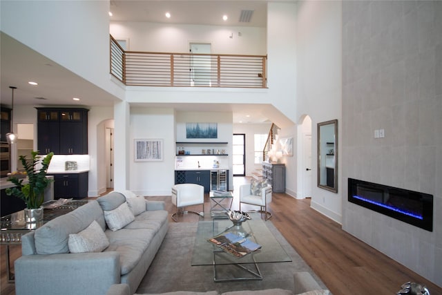 3314 Arbor St, Houston, TX 77004 - living room featuring arched walkways, a towering ceiling, a tiled fireplace, wood finished floors, and recessed lighting