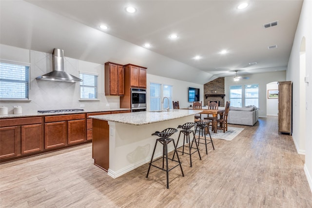 2821 Redbud Ln, Melissa, TX 75454 - kitchen with wall chimney range hood, a ceiling fan, brown cabinetry, light wood-style floors, and recessed lighting