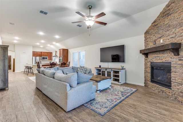 2821 Redbud Ln, Melissa, TX 75454 - living area featuring lofted ceiling, ceiling fan, light wood-type flooring, and a stone fireplace
