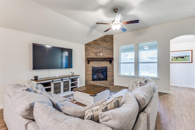 2821 Redbud Ln, Melissa, TX 75454 - living room featuring a ceiling fan, vaulted ceiling, wood finished floors, a stone fireplace, and arched walkways