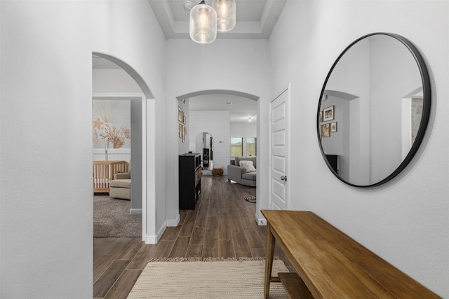 5311 Latigo Ct, Alvin, TX 77511 - hallway with wood finish floors, a towering ceiling, arched walkways, a chandelier, and a raised ceiling