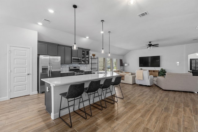 5311 Latigo Ct, Alvin, TX 77511 - kitchen with stainless steel appliances, light countertops, a large island with sink, a ceiling fan, and a breakfast bar