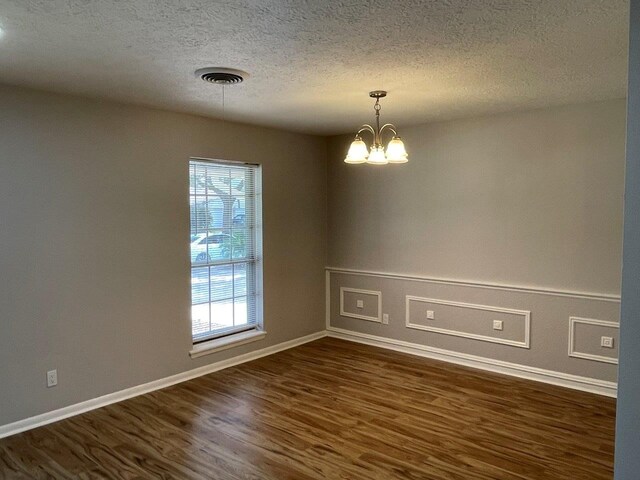 2202 Mockingbird Ln, Baytown, TX 77520 - unfurnished room with dark wood-style floors, a textured ceiling, and a chandelier