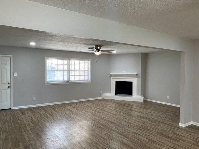 2202 Mockingbird Ln, Baytown, TX 77520 - unfurnished living room featuring a textured ceiling, ceiling fan, dark wood-type flooring, and a fireplace with raised hearth