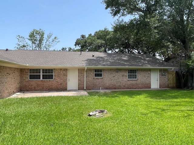2202 Mockingbird Ln, Baytown, TX 77520 - back of property featuring brick siding, a lawn, a patio area, and a shingled roof
