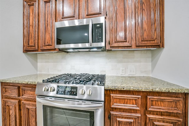 2531 Llano Springs Dr, Katy, TX 77494 - kitchen with appliances with stainless steel finishes, tasteful backsplash, and light stone counters