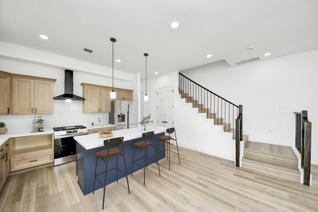 1913 W St, Houston, TX 77026 - kitchen featuring wall chimney range hood, stainless steel appliances, light wood-style flooring, light countertops, and a breakfast bar area