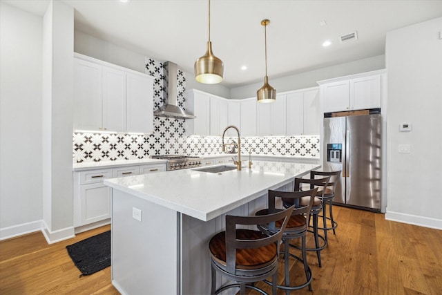824 Wakefield Dr Unit A, Houston, TX 77018 - kitchen with stainless steel fridge, wall chimney exhaust hood, decorative backsplash, a center island with sink, and a breakfast bar