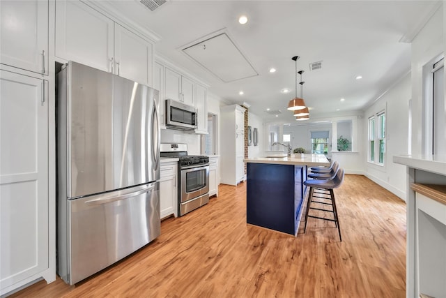 724 E 21st St, Houston, TX 77008 - kitchen featuring stainless steel appliances, light wood-style flooring, white cabinetry, a center island with sink, and recessed lighting