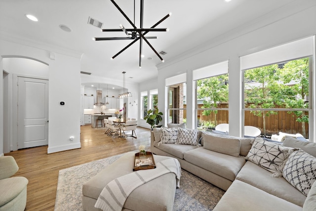 8421 Moritz Grn, Houston, TX 77055 - living area featuring a chandelier, crown molding, arched walkways, recessed lighting, and light wood-type flooring