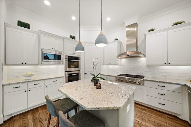 8421 Moritz Grn, Houston, TX 77055 - kitchen with stainless steel appliances, wall chimney range hood, ornamental molding, white cabinetry, and a breakfast bar area