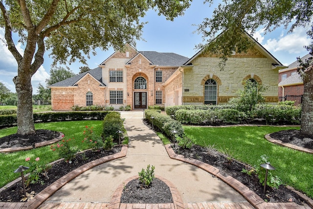 7010 Mcclellan Ln, Sugar Land, TX 77479 - view of front of property with a front yard, french doors, stone siding, and brick siding