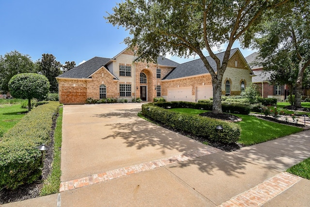7010 Mcclellan Ln, Sugar Land, TX 77479 - view of front of house with brick siding, concrete driveway, an attached garage, and a shingled roof