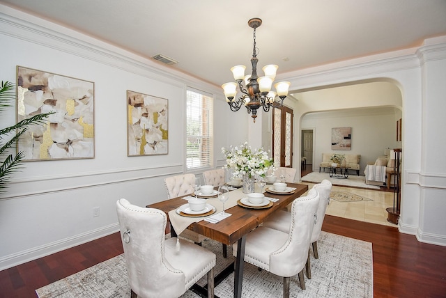 7010 Mcclellan Ln, Sugar Land, TX 77479 - dining room featuring arched walkways, a chandelier, wood finished floors, and crown molding