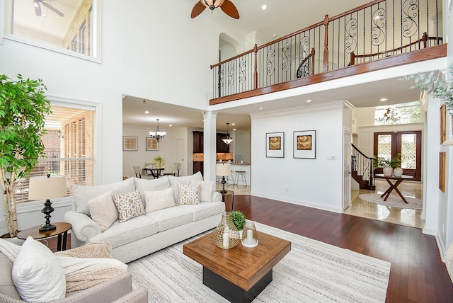 7010 Mcclellan Ln, Sugar Land, TX 77479 - living room featuring ceiling fan, a towering ceiling, wood-type flooring, stairs, and a chandelier