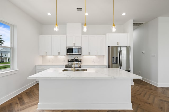 23107 Miramar Cir, Galveston, TX 77554 - kitchen featuring appliances with stainless steel finishes, white cabinets, an island with sink, decorative light fixtures, and recessed lighting