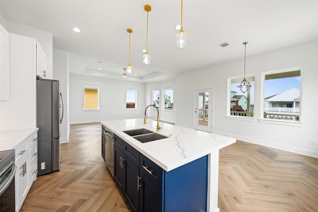 23107 Miramar Cir, Galveston, TX 77554 - kitchen with stainless steel appliances, a raised ceiling, recessed lighting, white cabinetry, and an island with sink
