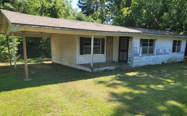 343 NW Martin Luther King Dr, De Kalb, TX 75559 - view of front of home featuring concrete block siding, a front yard, and roof with shingles