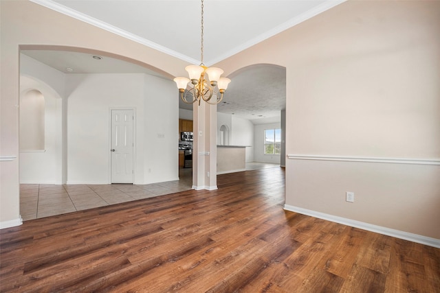 12610 Hobbs Terrace Dr, Tomball, TX 77377 - unfurnished room featuring a chandelier, arched walkways, wood finished floors, and crown molding